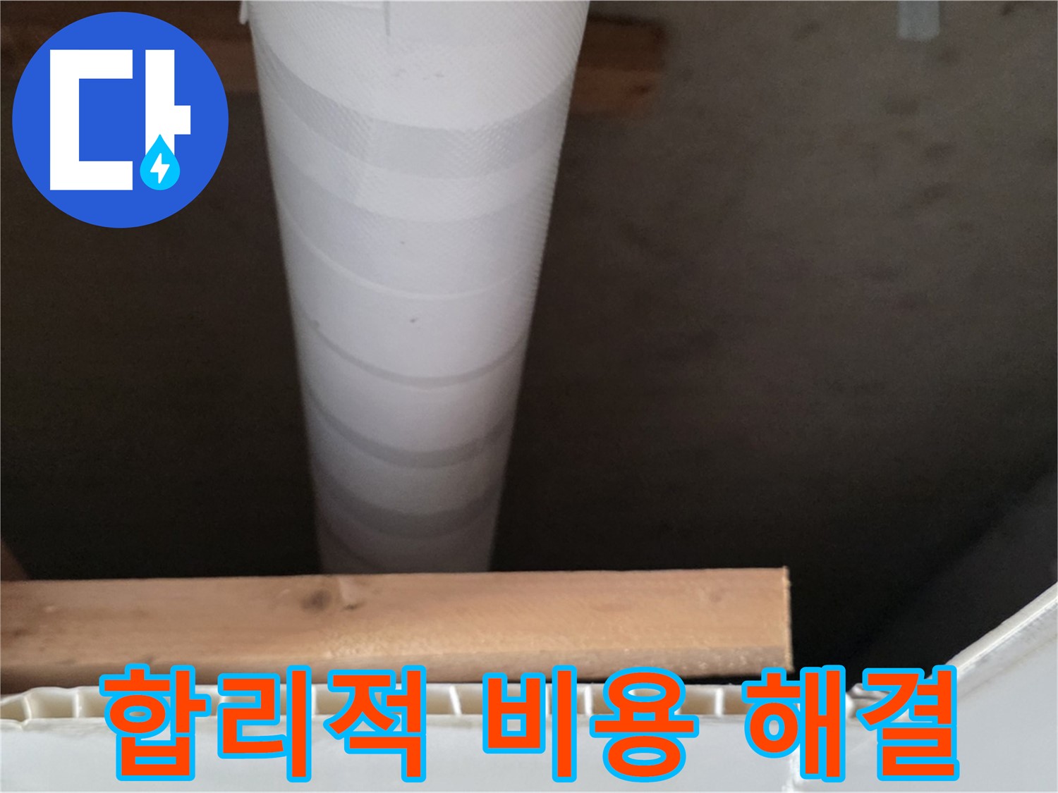 천장 마감재 사이로 보이는 수직 배관과 목재 프레임의 모습입니다.