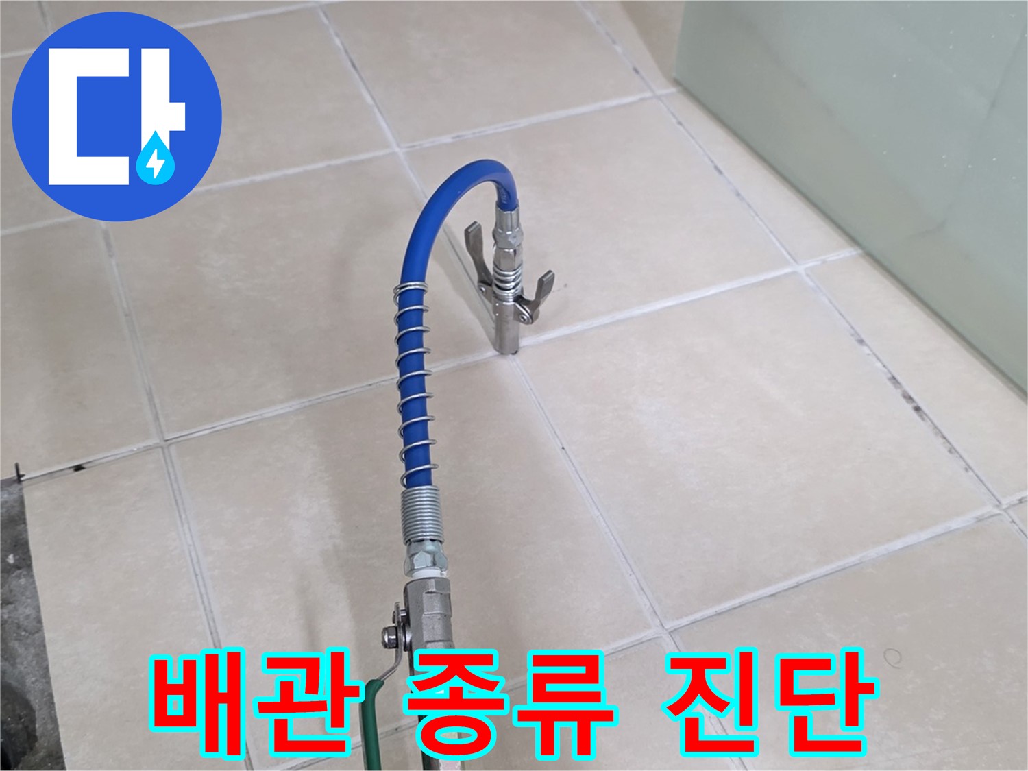 밝은색 화장실 타일 위에 놓인 파란색 호스와 금속 부품 장비