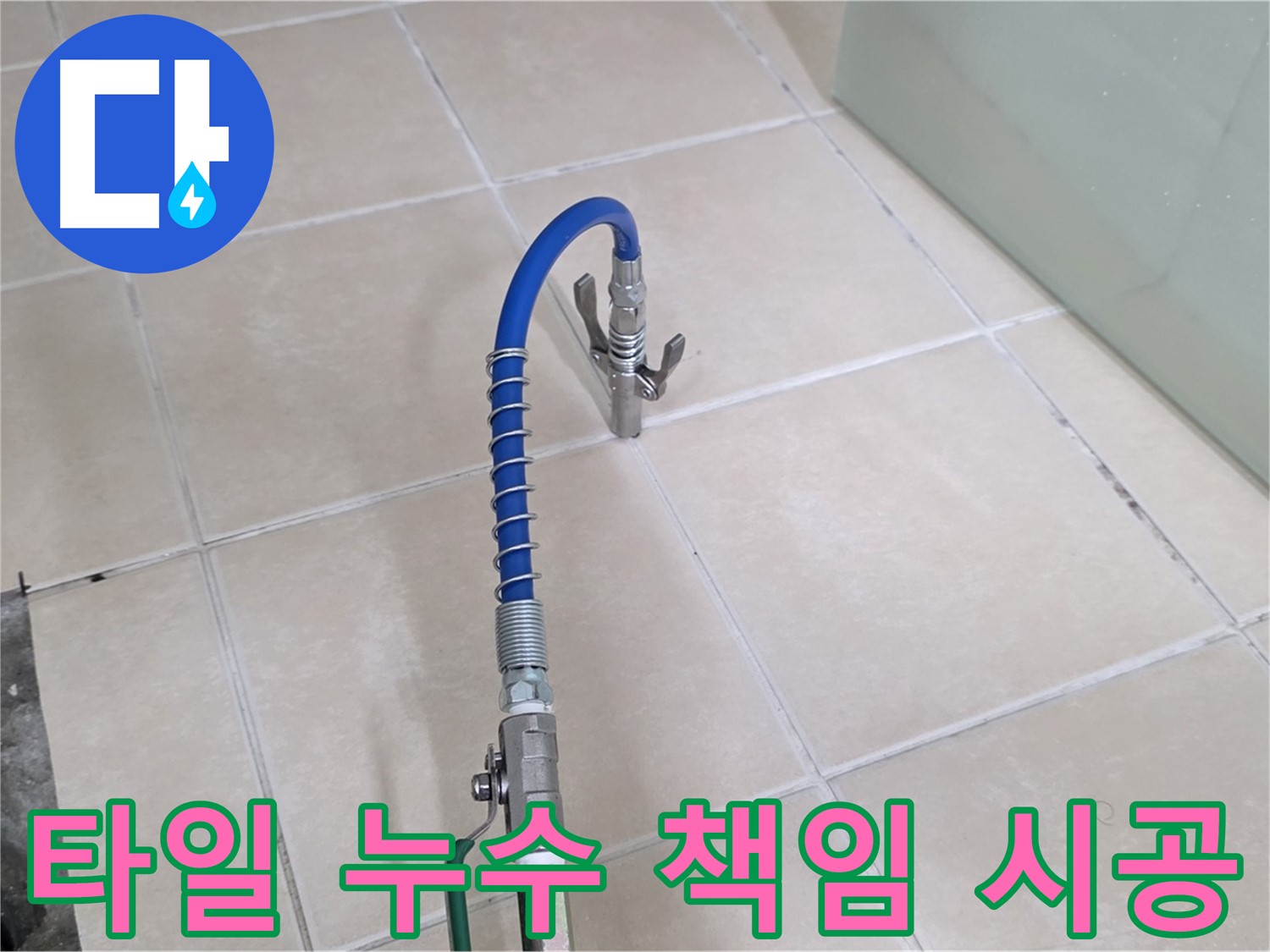 타일 바닥에 놓인 파란색 호스와 금속 연결 장비