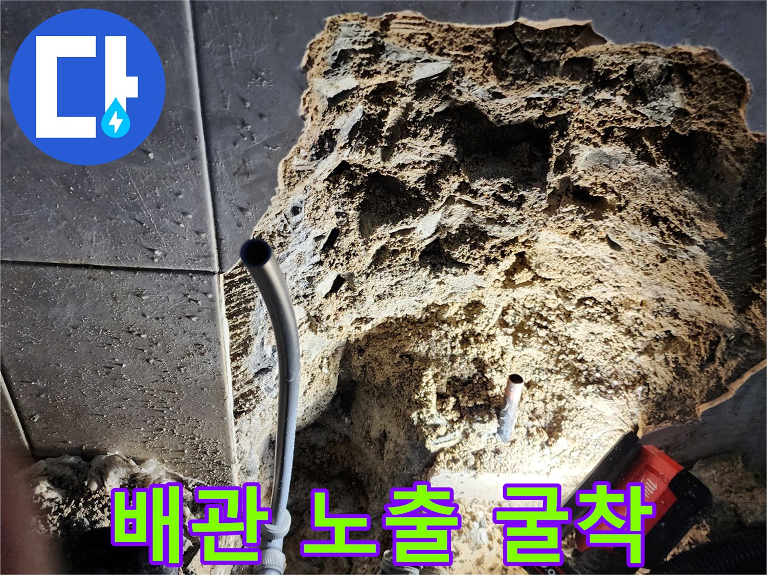 벽면 타일 아래 노출된 하수 배관과 작업용 전동 도구