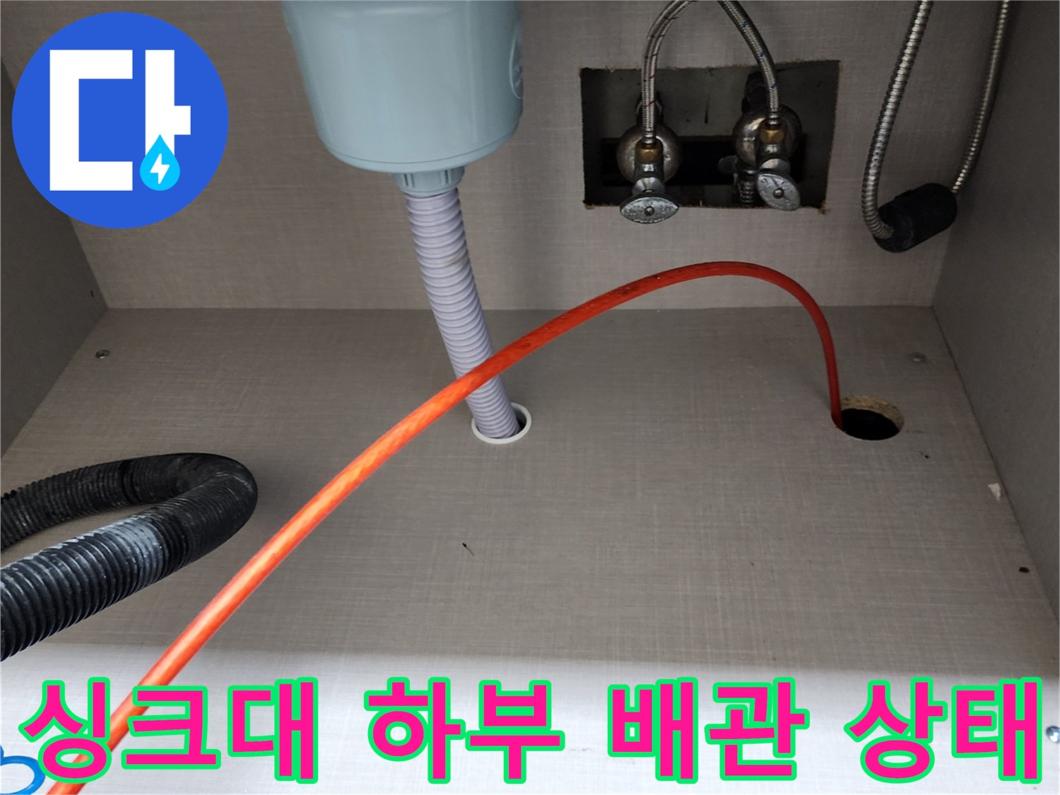 싱크대 하부장 내부의 수전 연결 호스와 배수관 모습