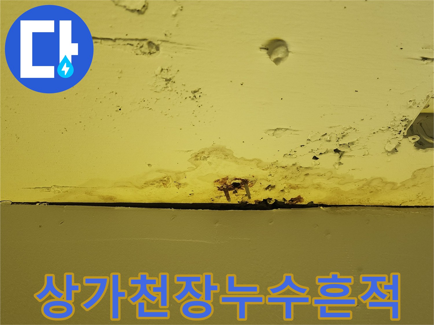 노란색 천장 마감재 하단에 발생한 습기 침투 및 변색 부위