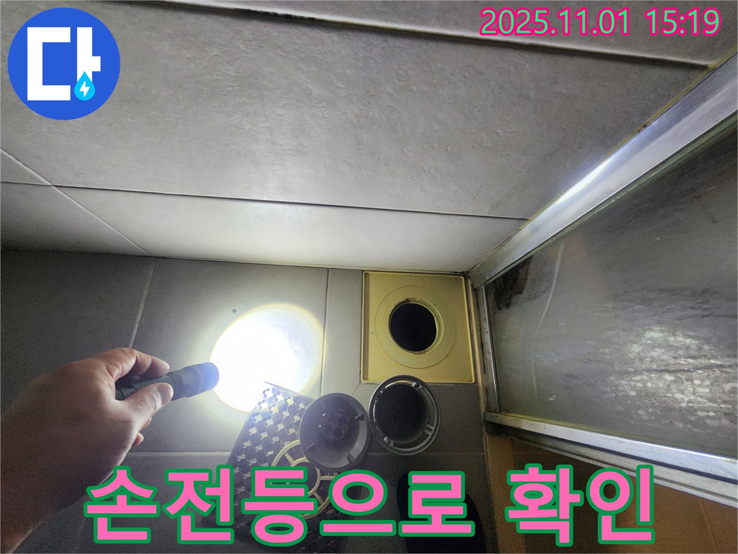 손전등을 사용하여 샤워실 배수구를 구석구석 확인하고 있습니다 - 어두운 곳도 놓치지 않습니다.
