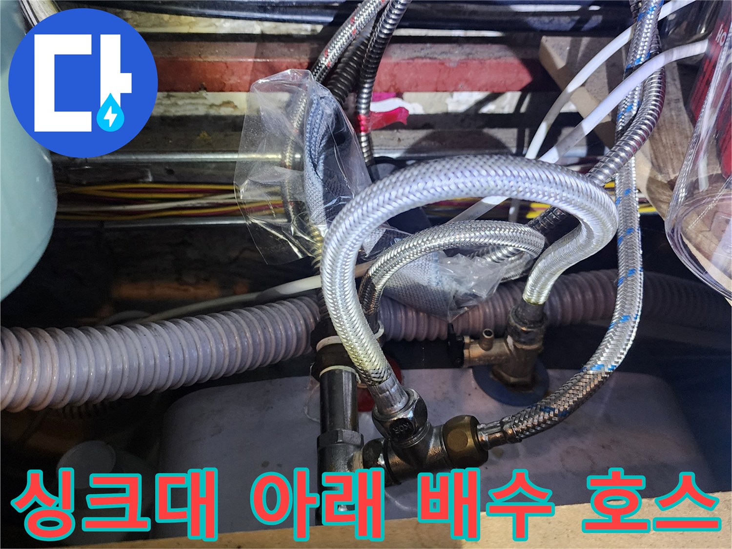 굴곡진 형태의 은색 자재와 회색 주름관이 연결된 싱크대 하단부