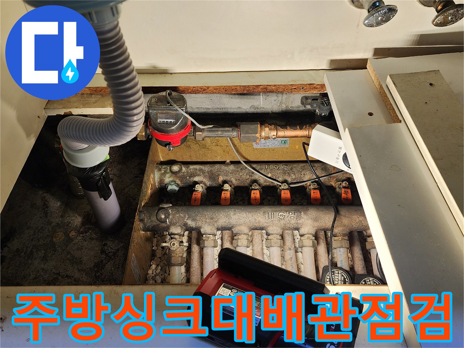 싱크대 아래 수도 밸브와 계량기가 보이는 배관함 내부 사진