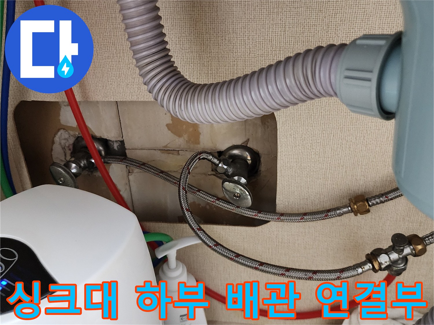 싱크대 아래 벽면 밸브와 연결된 금속 호스 및 주름관 모습입니다.