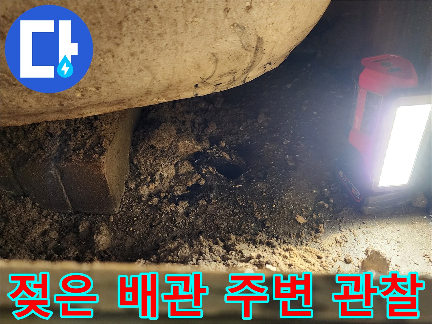 손전등으로 조명한-축축하게 젖어 있는 배관 및 토사 부위