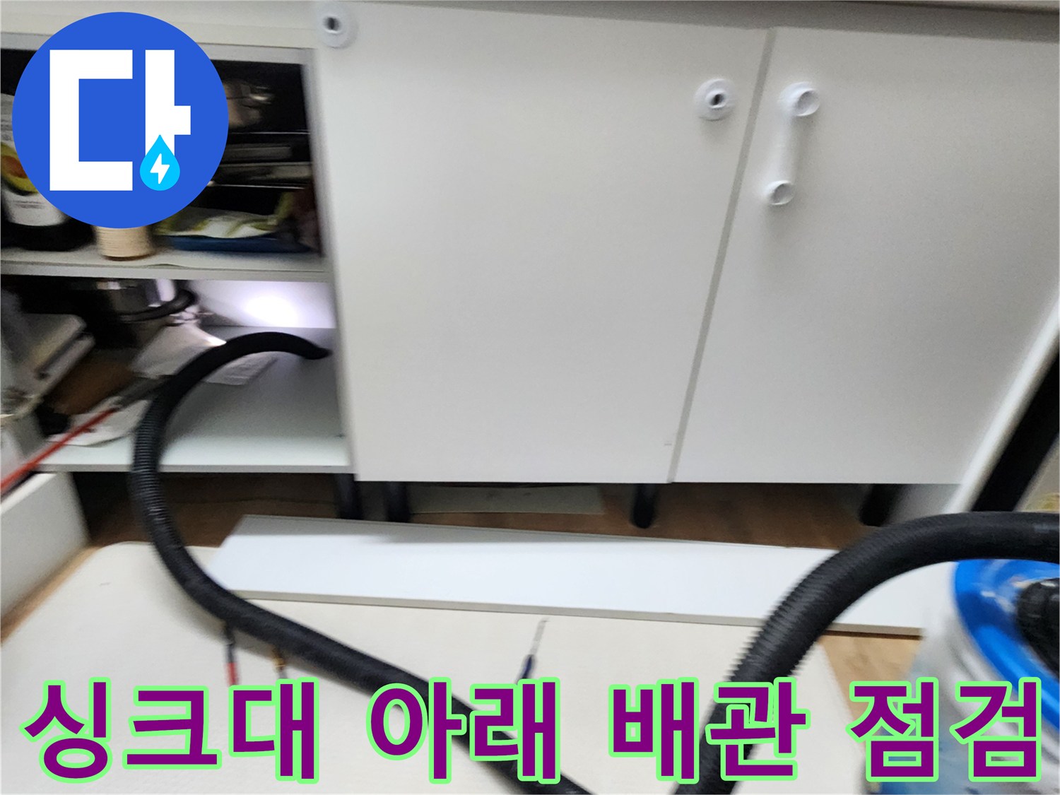 싱크대 하부장 바닥의 배관 호스 연결 부위 사진입니다.