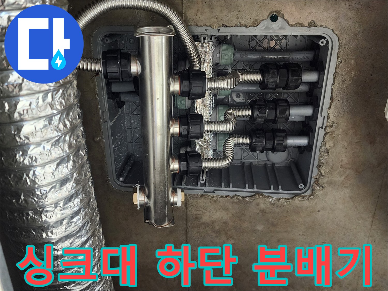 주방 싱크대 아래 매립된 스테인리스 분배기와 배관 연결 부위 모습입니다.