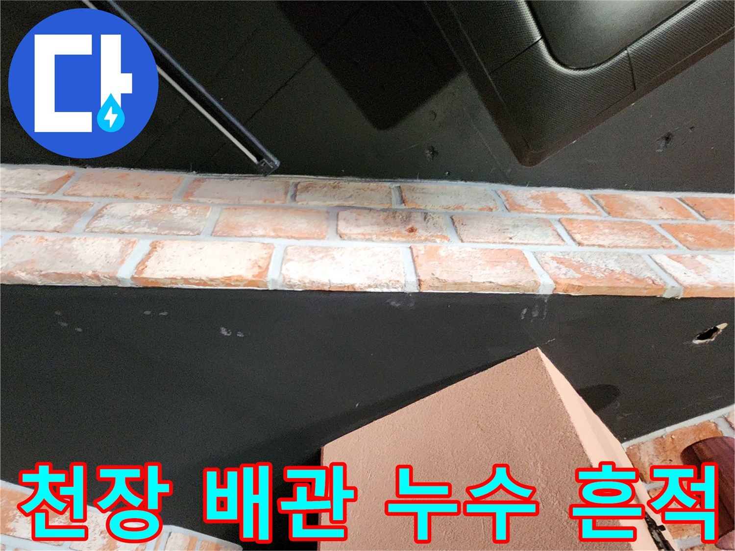검은색 천장 구조물과 벽돌 벽면의 습기 오염 부위