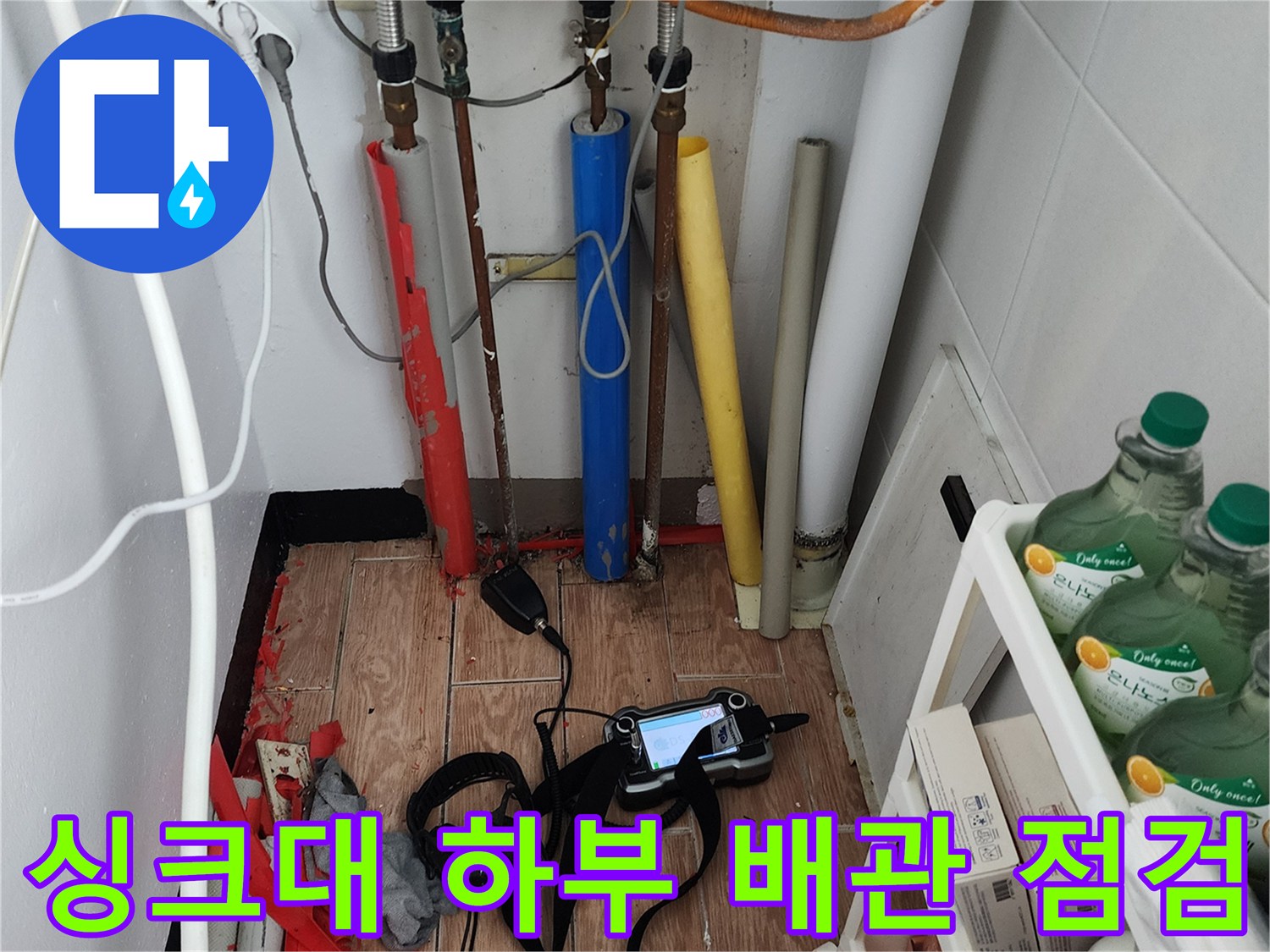 주방 싱크대 아래 복잡한 배관들과 누수 탐지용 장비 세트