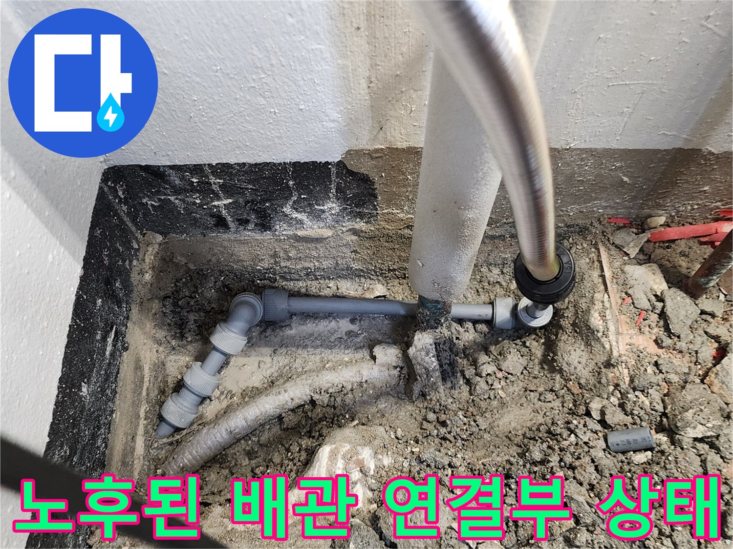 지면 아래 노출된 회색 배관과 은색 호스의 연결 부위 사진입니다.