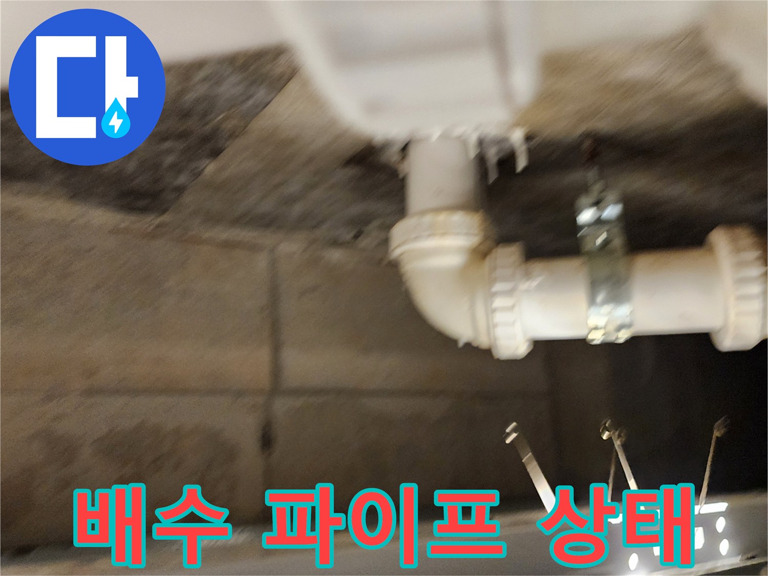 천장 슬라브에 연결된 흰색 배수 파이프와 금속 고정 장치