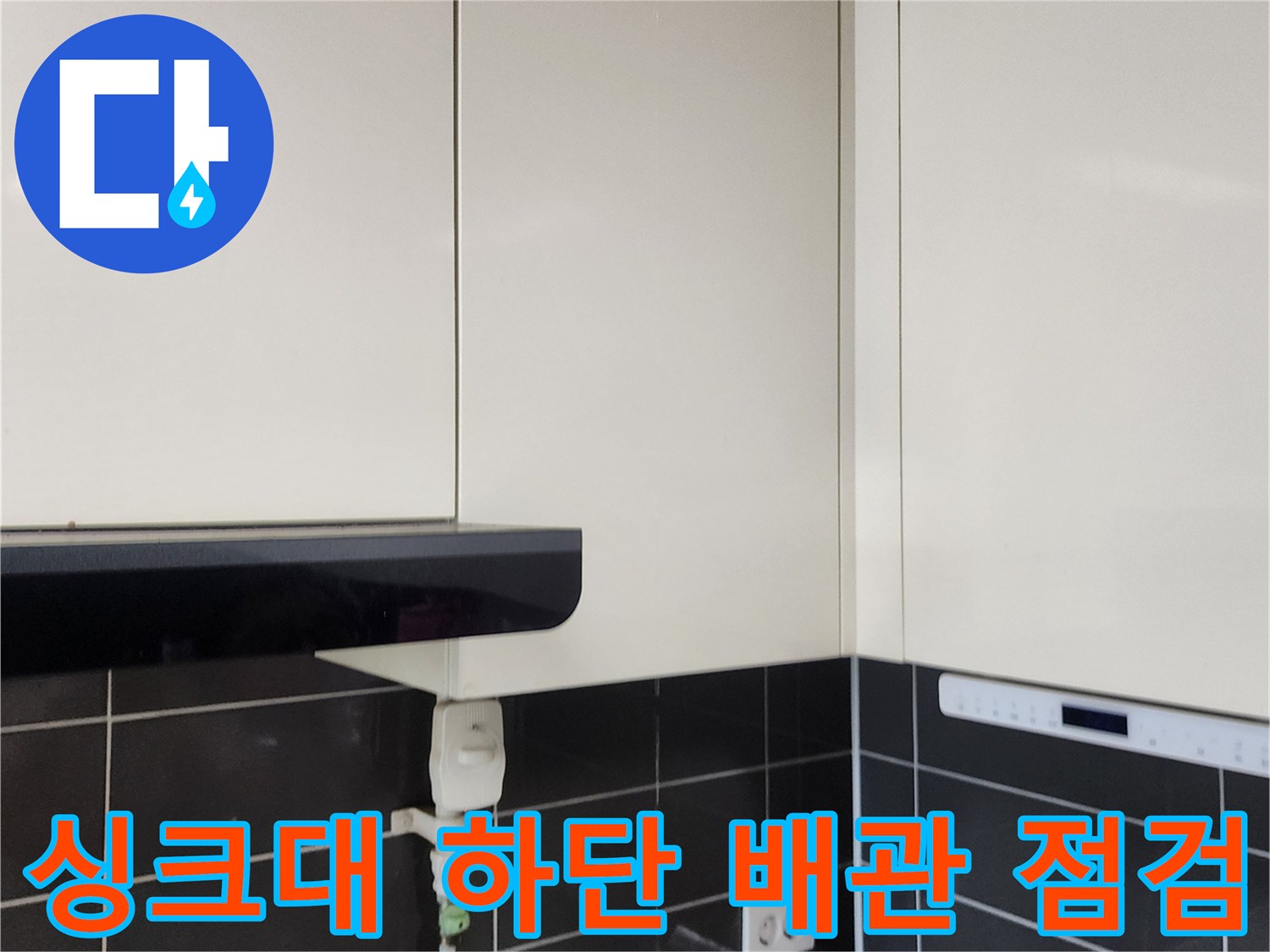 주방 싱크대 아래쪽 콘센트와 타일 벽면의 상세 모습