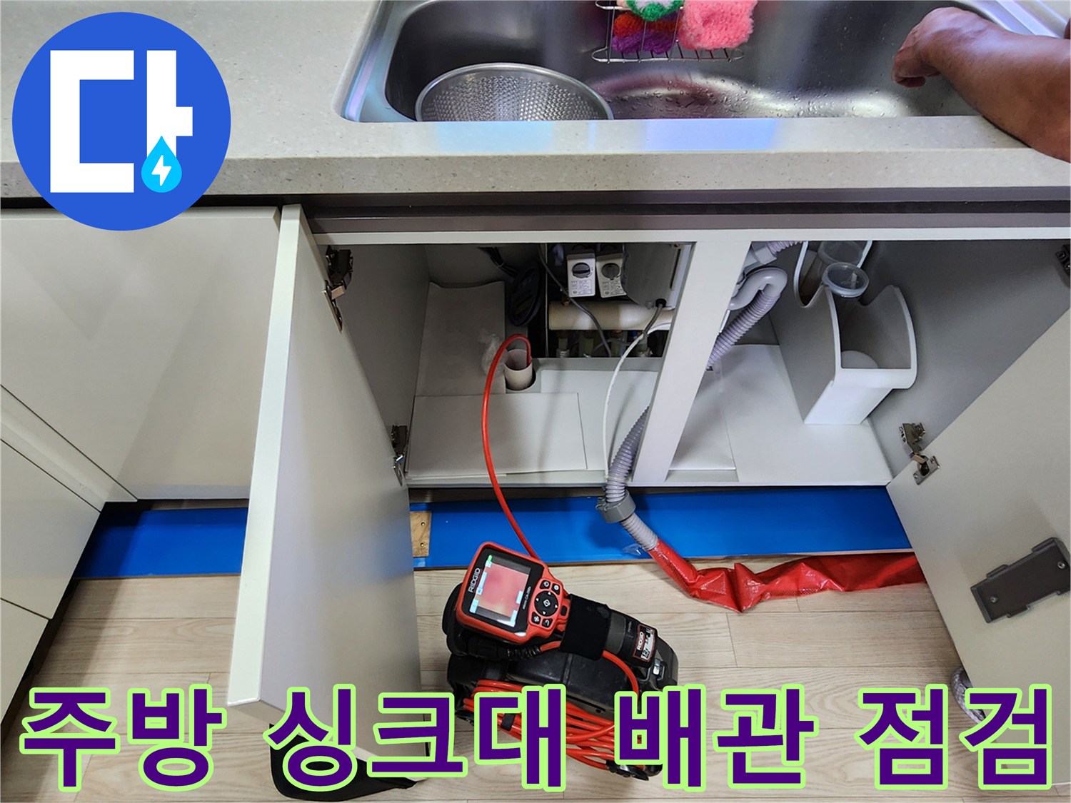 주방 싱크대 하부장 내부의 배관과 가스식 탐지기 장비 모습