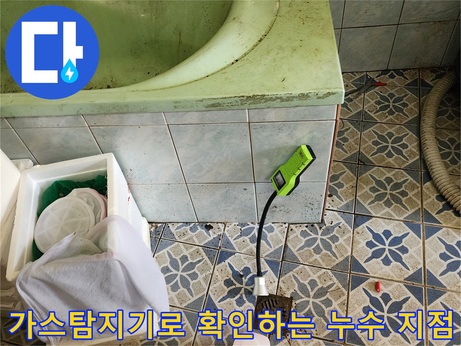 욕실 바닥 타일 위에서 가스 탐지기를 사용해 배관 상태를 점부록하는 모습