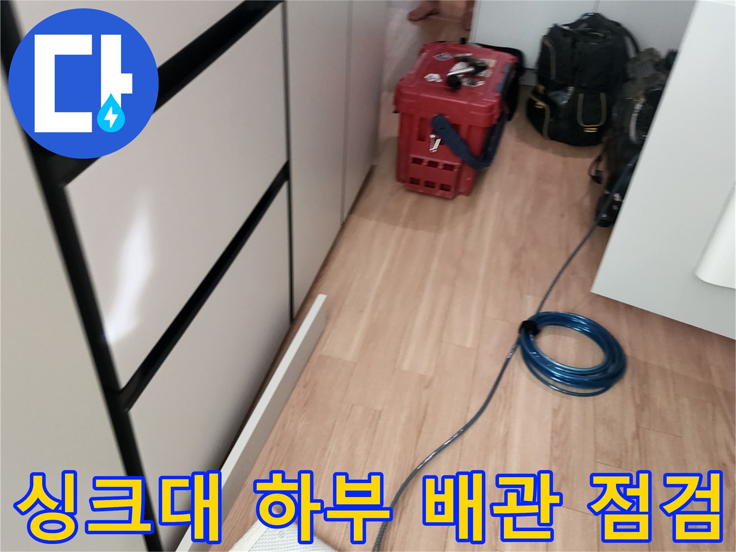 싱크대 아래 공간에 배치된 누수 탐지용 공압 장비와 호스입니다.