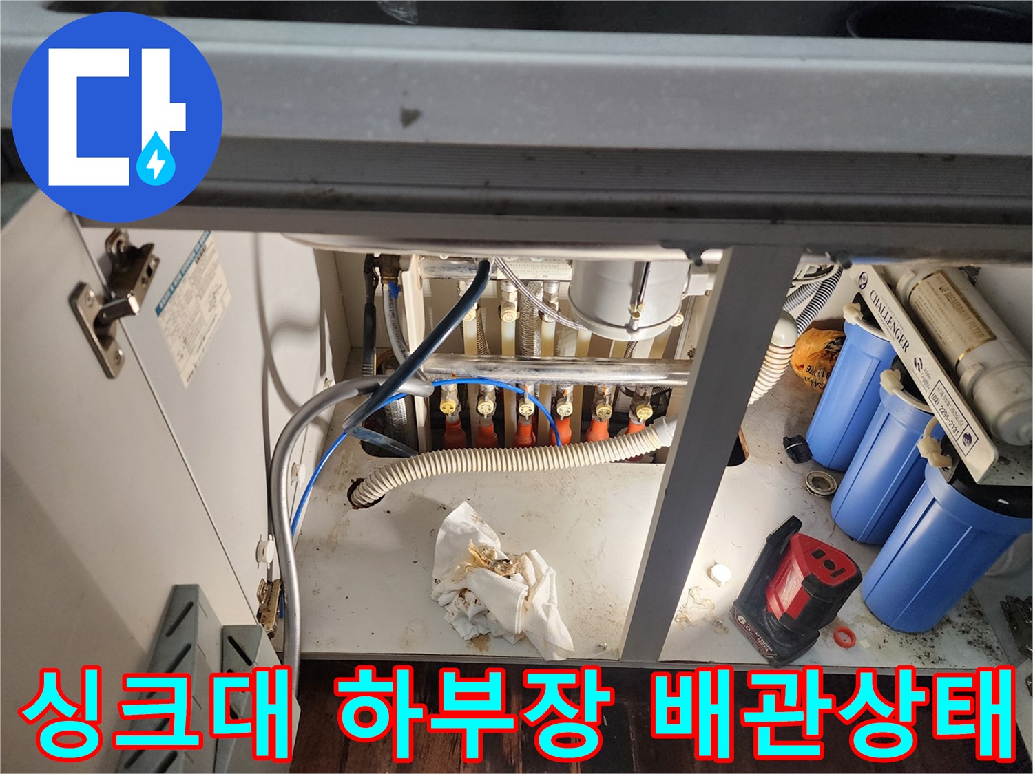 주방 싱크대 하부의 복잡한 배관과 정수기 필터 모습