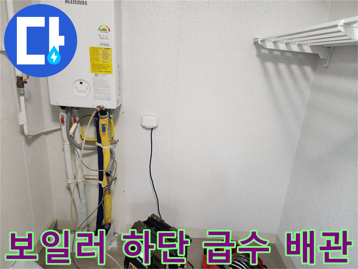 벽면에 설치된 보일러와 연결된 여러 가지 색상의 배관 및 작업 장비 모습입니다.