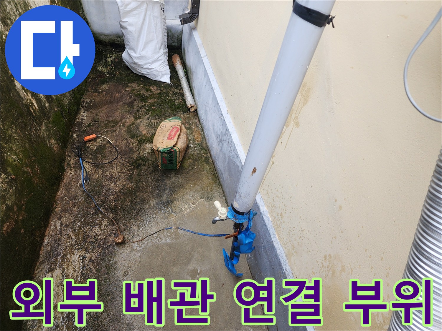 건물 외벽 옆에 설치된 흰색 배관과 파란색 연결 부속 상태를 보여주는 사진입니다.