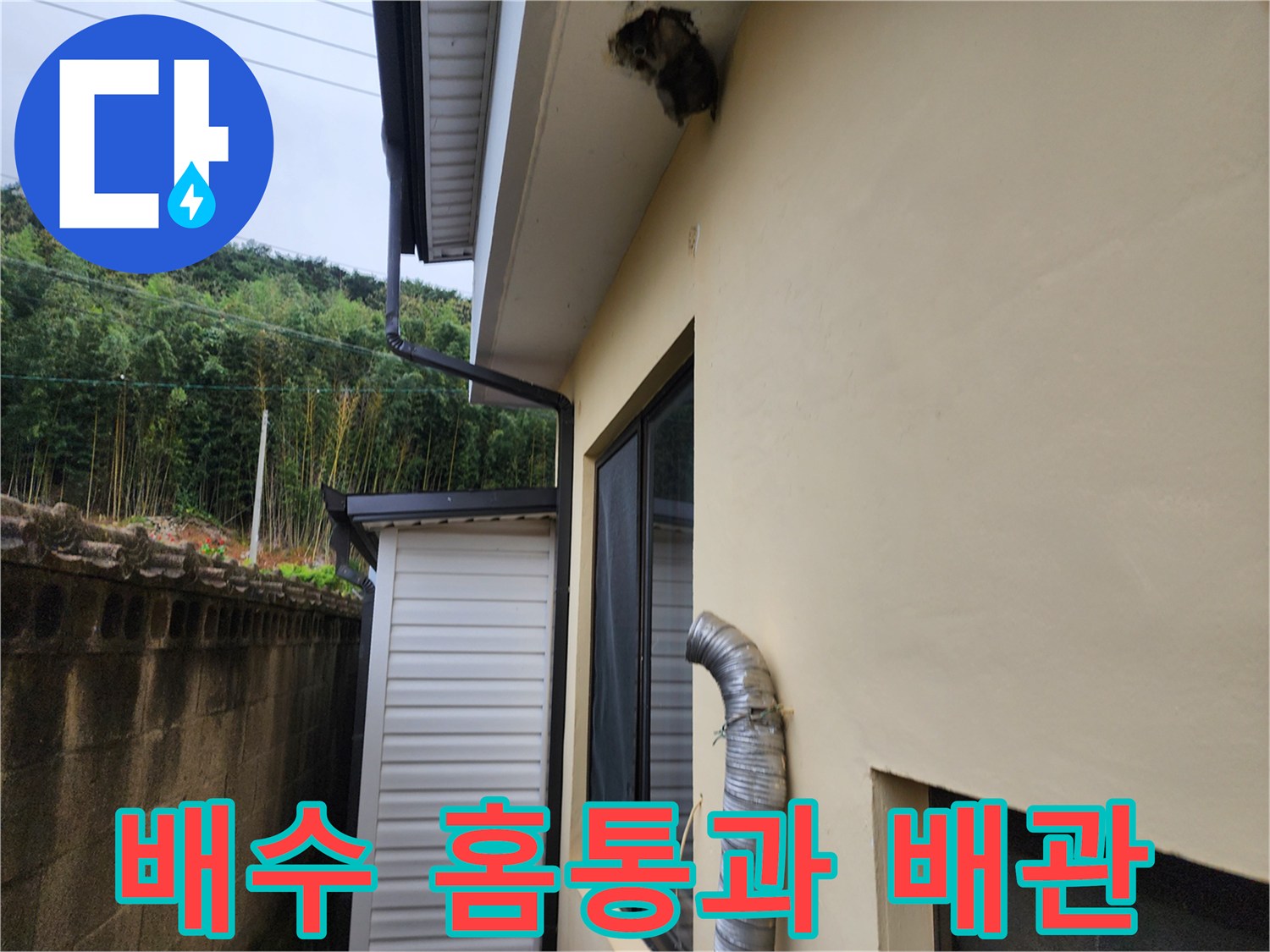 벽면 홈통과 연결된 유연한 은색 배수관의 근접 촬영