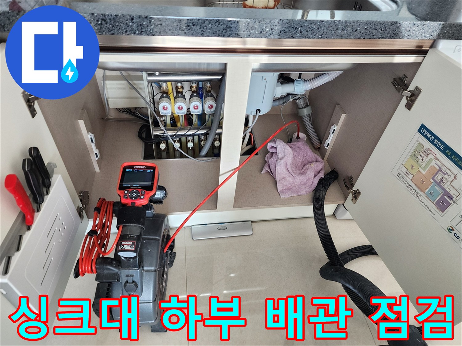 싱크대 밑 배관 연결 부위와 내시경 장비가 배치된 작업 현장 사진입니다.