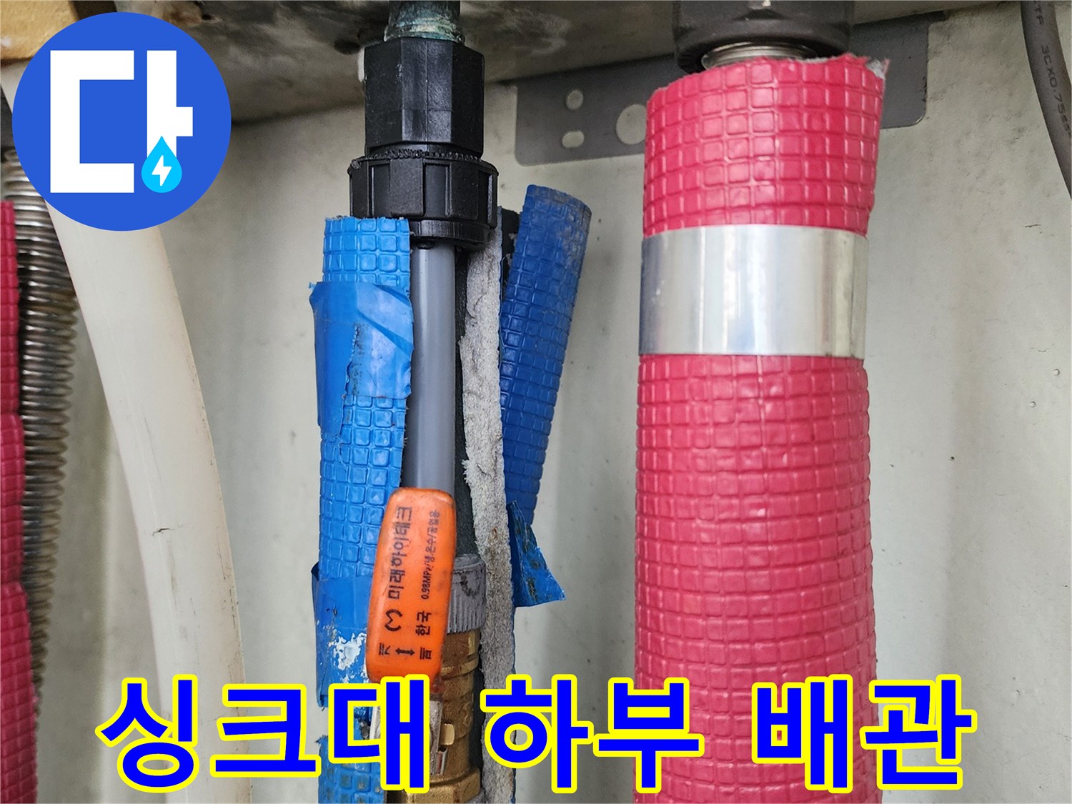싱크대-하부의-분홍색-단열재가-씌워진-배관과-파란색-보온재-배관 모습