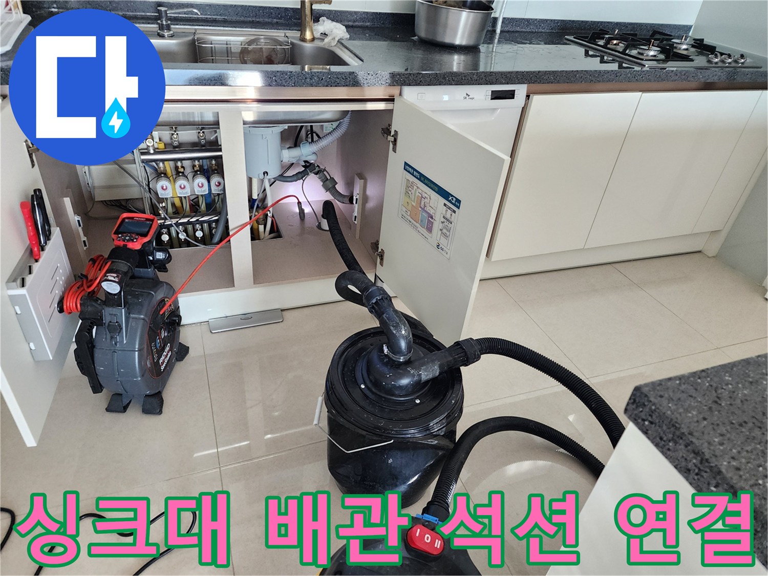 주방 싱크대 하부장 내부의 배관과 석션 호스가 연결된 모습입니다.