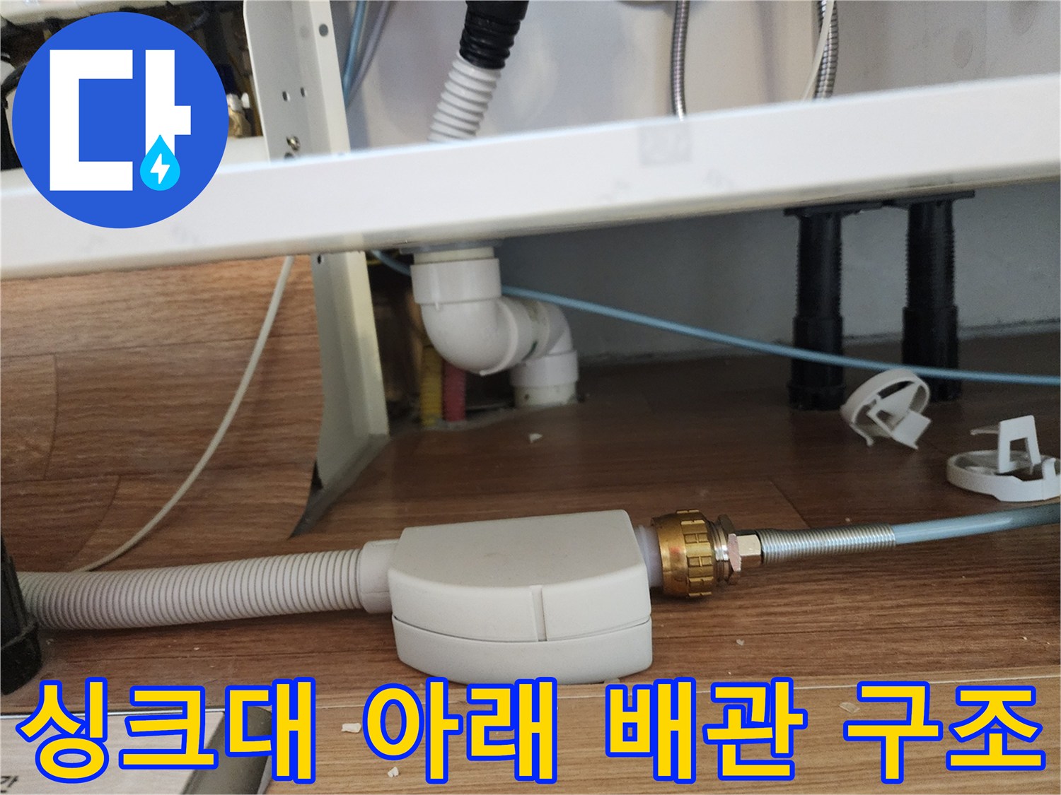 바닥에 설치된 흰색 주름관과 금속 연결 부품의 모습