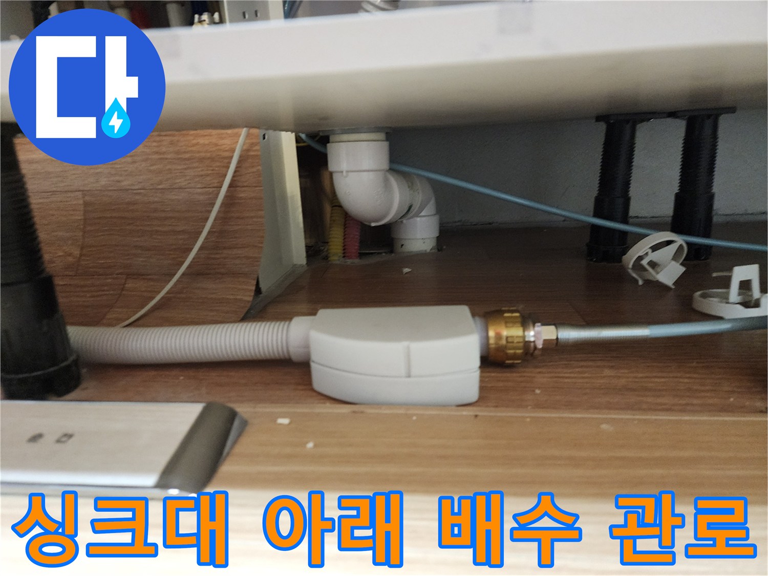 싱크대 밑바닥에 연결된 흰색 배관과 주름 호스 부위