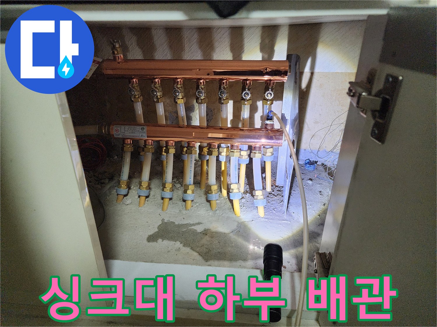 싱크대 아래 설치된 구리색 분배기와 연결된 여러 갈래의 배관들입니다.
