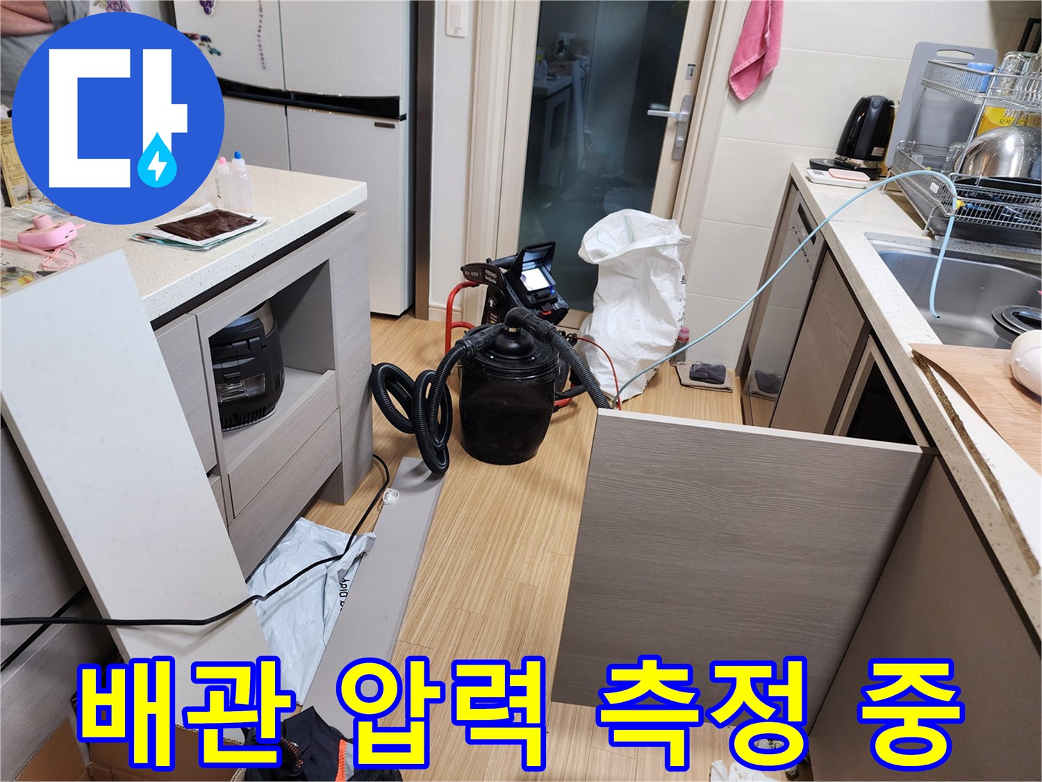 싱크대 하단 배관에 연결된 공압 테스트 장비와 호스입니다.