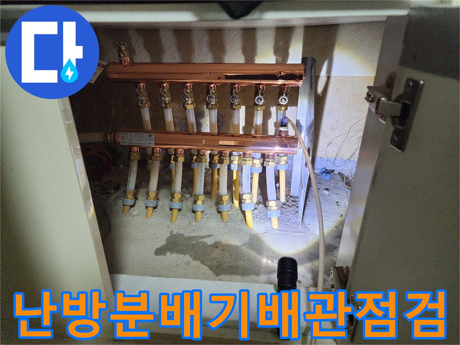 싱크대 하단부에 노출된 구리 분배기와 연결 배관의 근접 사진