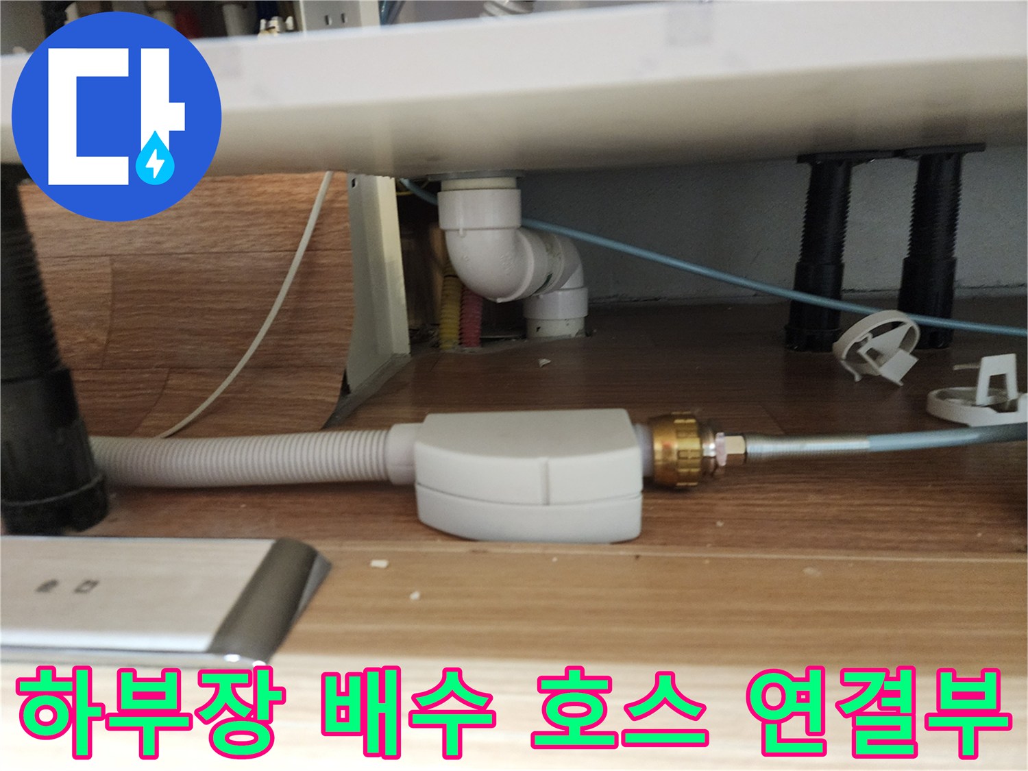 싱크대 하부의 흰색 플라스틱 배관과 주름진 호스 연결 상태