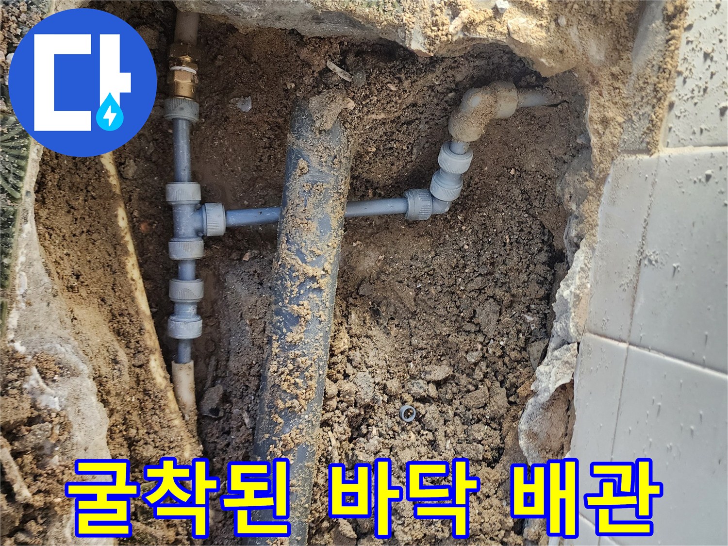 흙과 자갈 사이로 노출된 수도용 엘보 부속 및 직선 배관