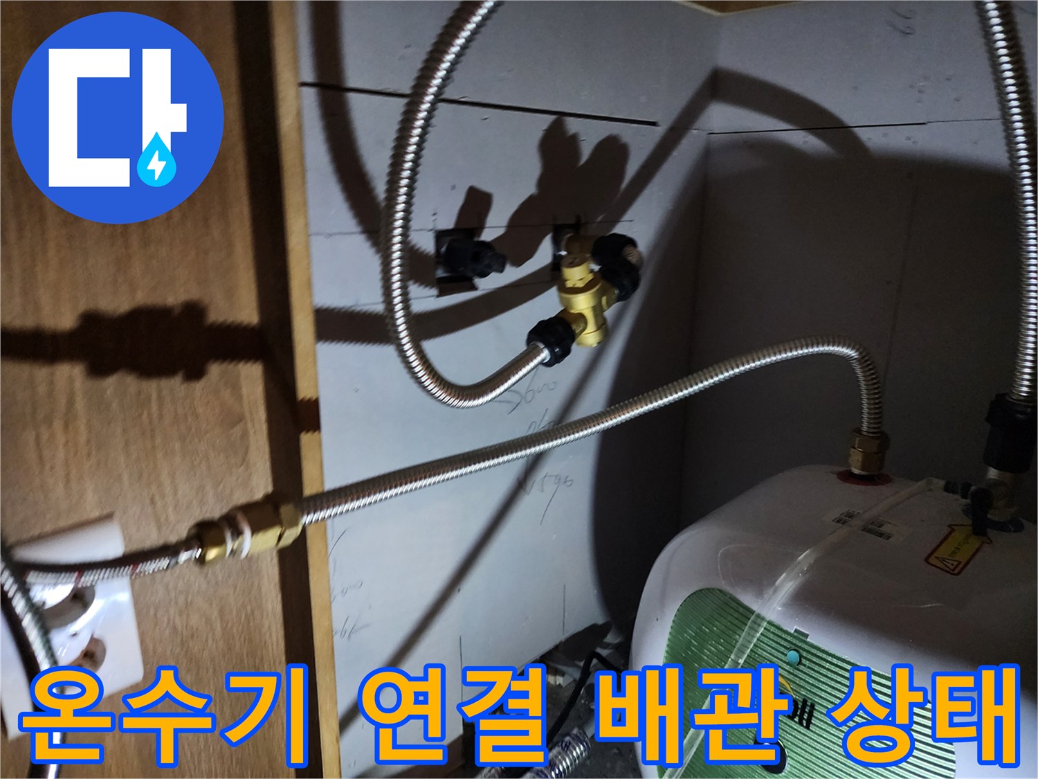 주방 하부장 내부-전기 온수기와 연결된 금속 호스의 접합 부위 모습