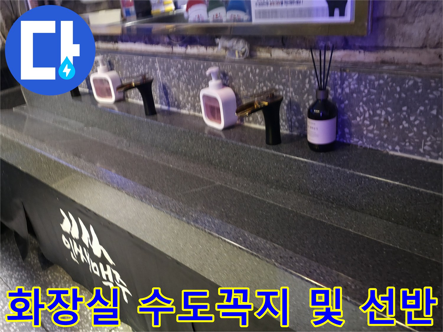 검은색 대리석 선반 위에 설치된 화장실 수전과 디퓨저
