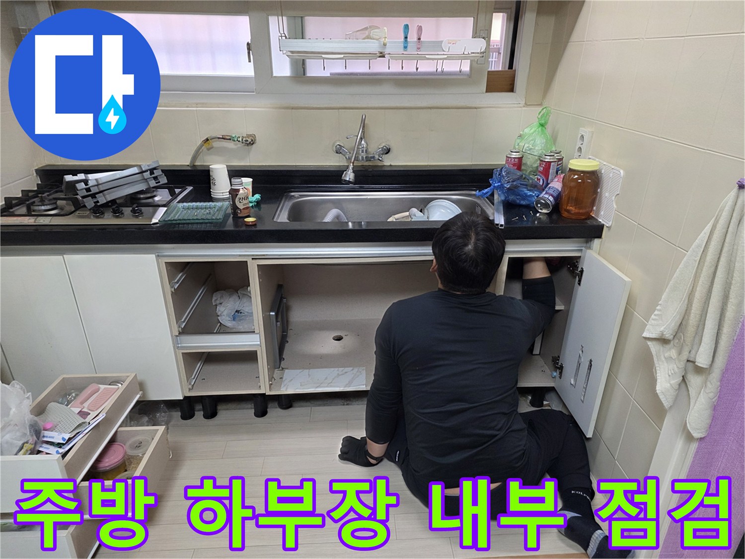 싱크대 밑 공간에서 배관의 누수 여부를 확인하기 위해 작업 중인 엔지니어