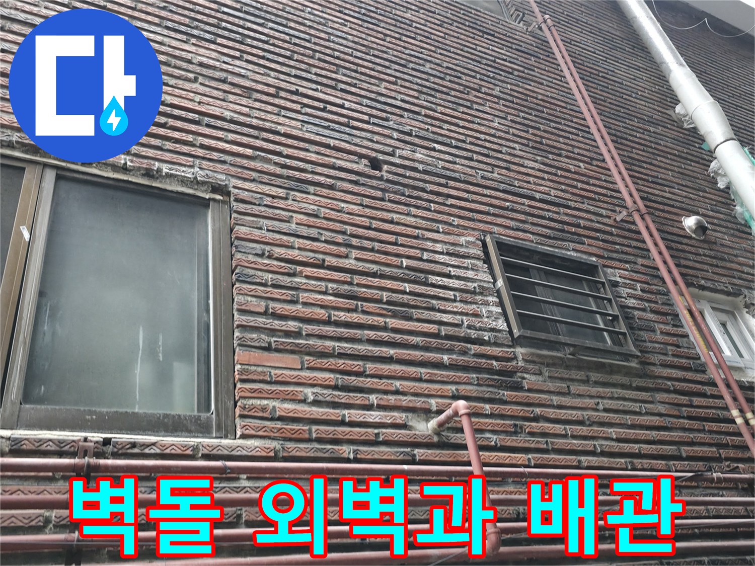 벽돌로 마감된 건물 외벽에 설치된 수직 배관 이미지