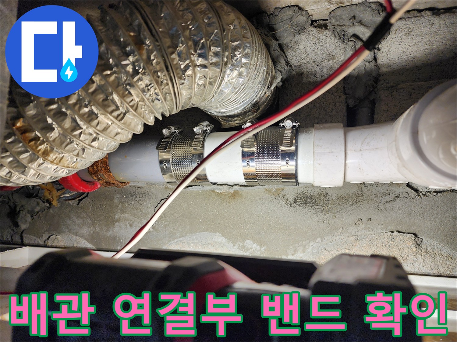 금속 밴드로 조여진 하수 배관의 연결 부위 상세 사진입니다.