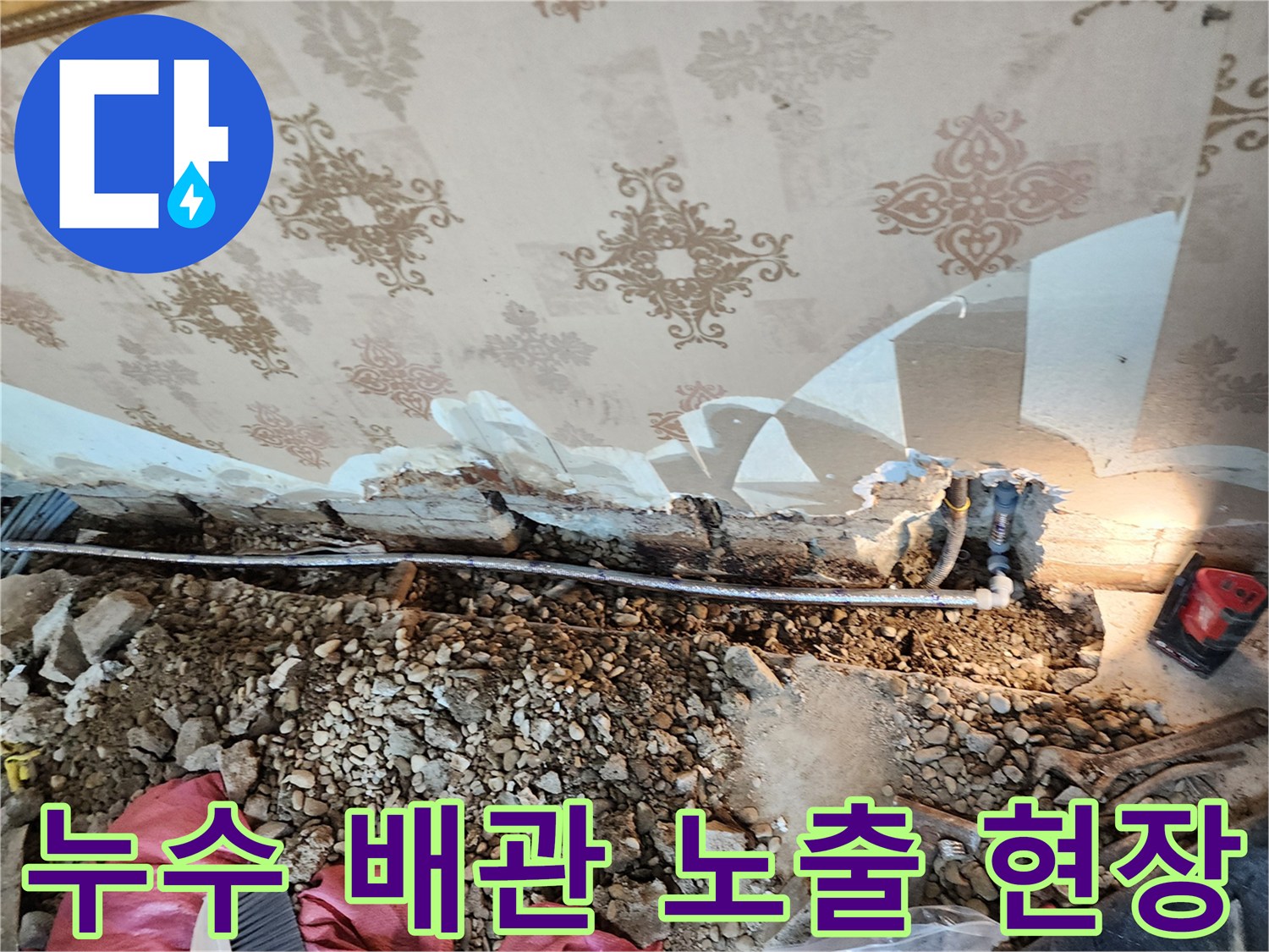 벽면 하단부의 젖은 벽지와 드러난 배관 부위