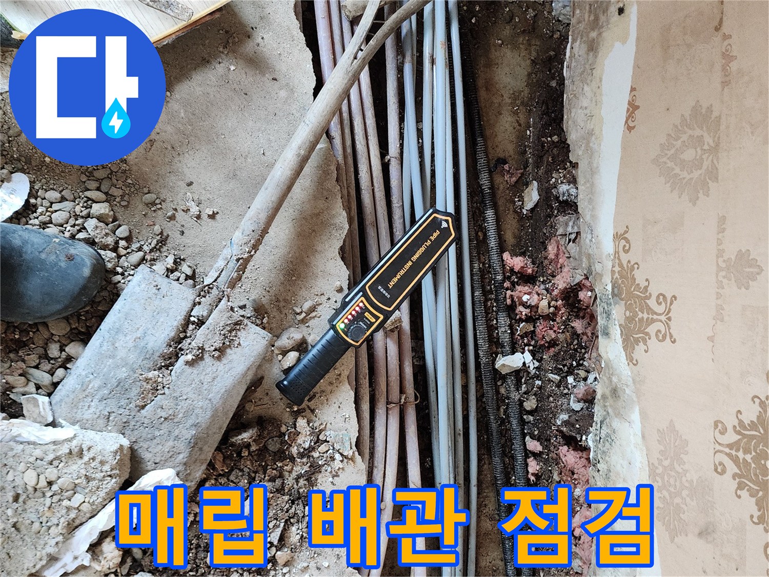 벽체 하단에 노출된 매립 배관과 탐지 장비의 모습