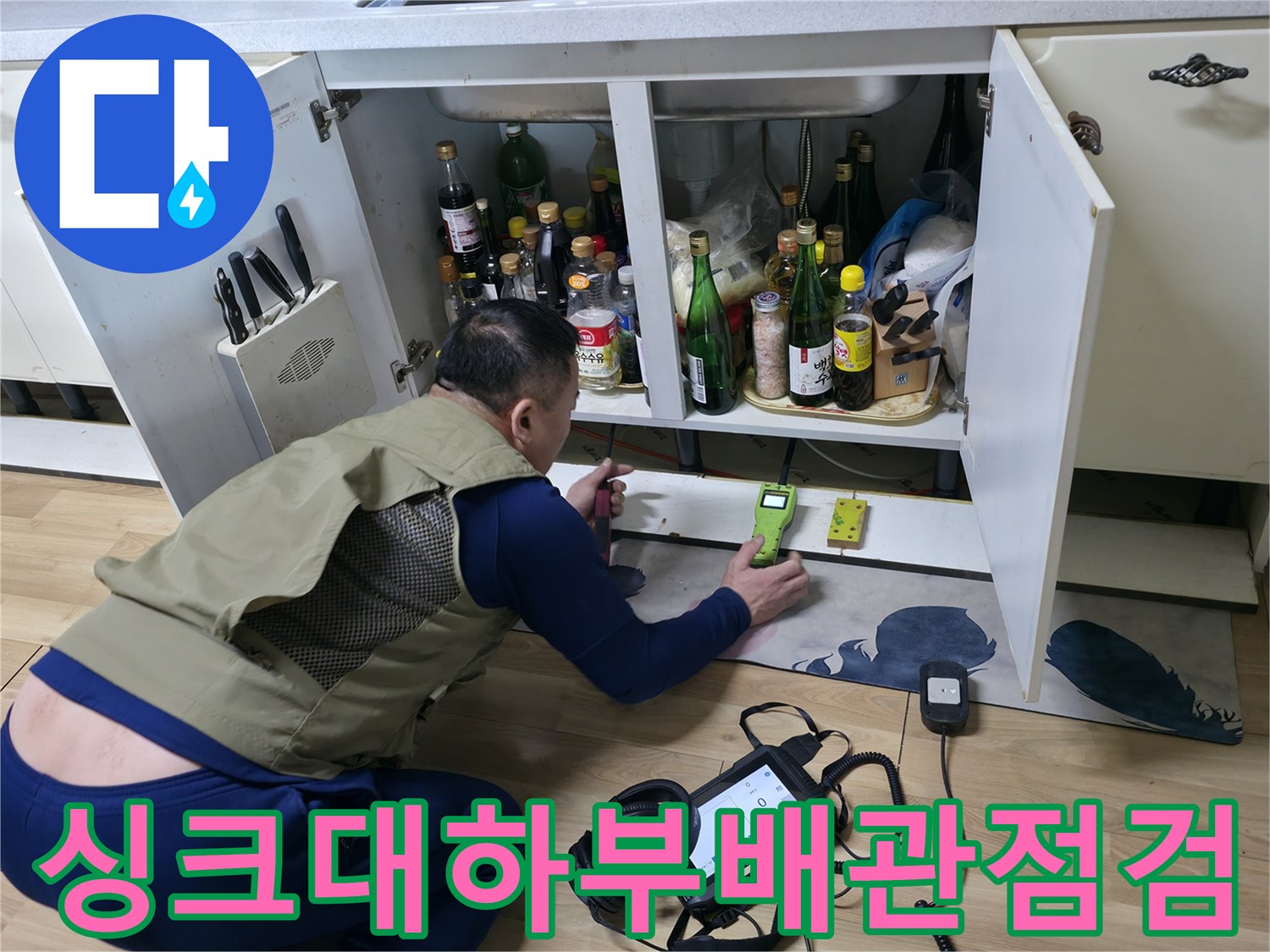 엔지니어가 엎드린 자세로 싱크대 하부 배관의 가스 반응을 확인하고 있습니다.