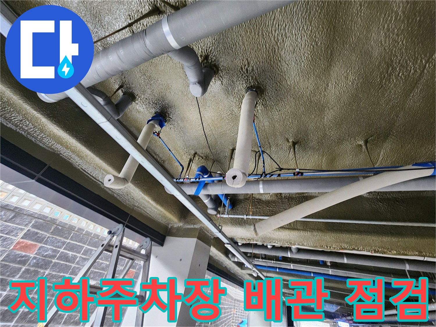지하주차장-천장에 설치된 복잡한 배관 시스템과 보온재 상태를 확인하는 모습
