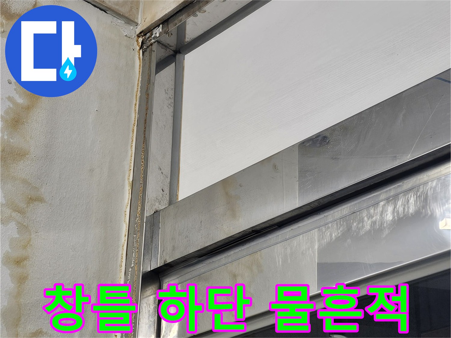 창틀 프레임 아래쪽 마감재의 갈색 누수 오염 흔적