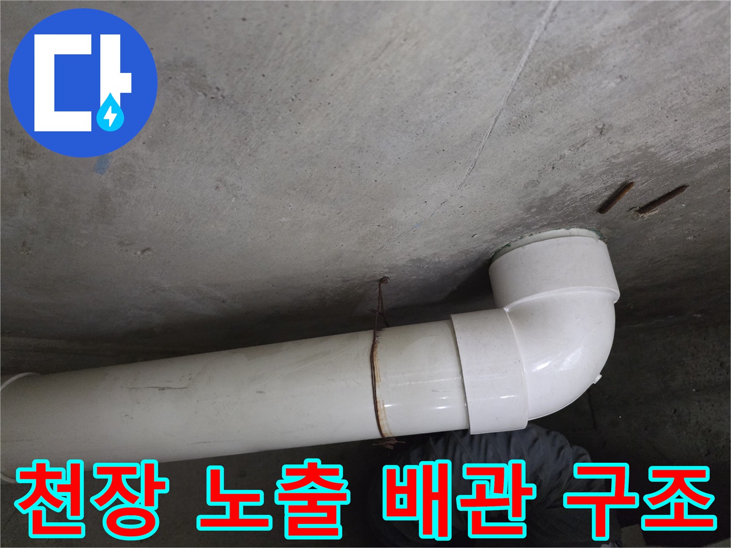 콘크리트 천장에 고정된 흰색 하수 배관의 연결 부위 촬영