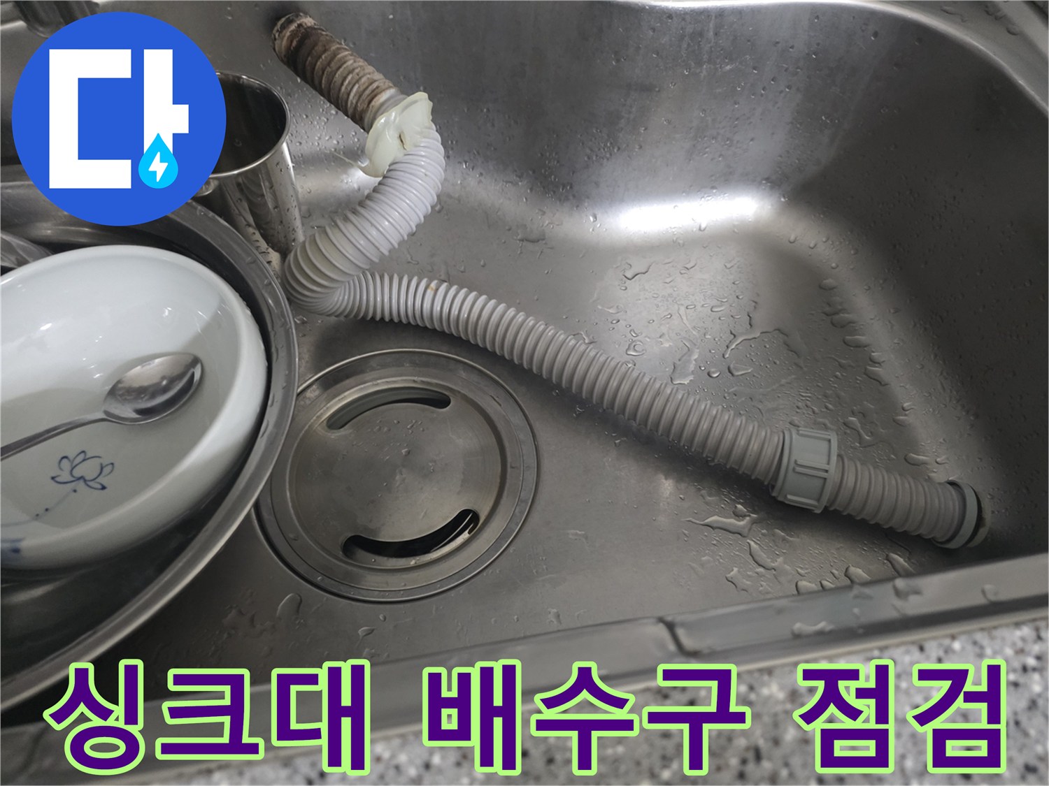 스테인리스 싱크볼 내부에 배치된 회색 주름관과 금속 용기