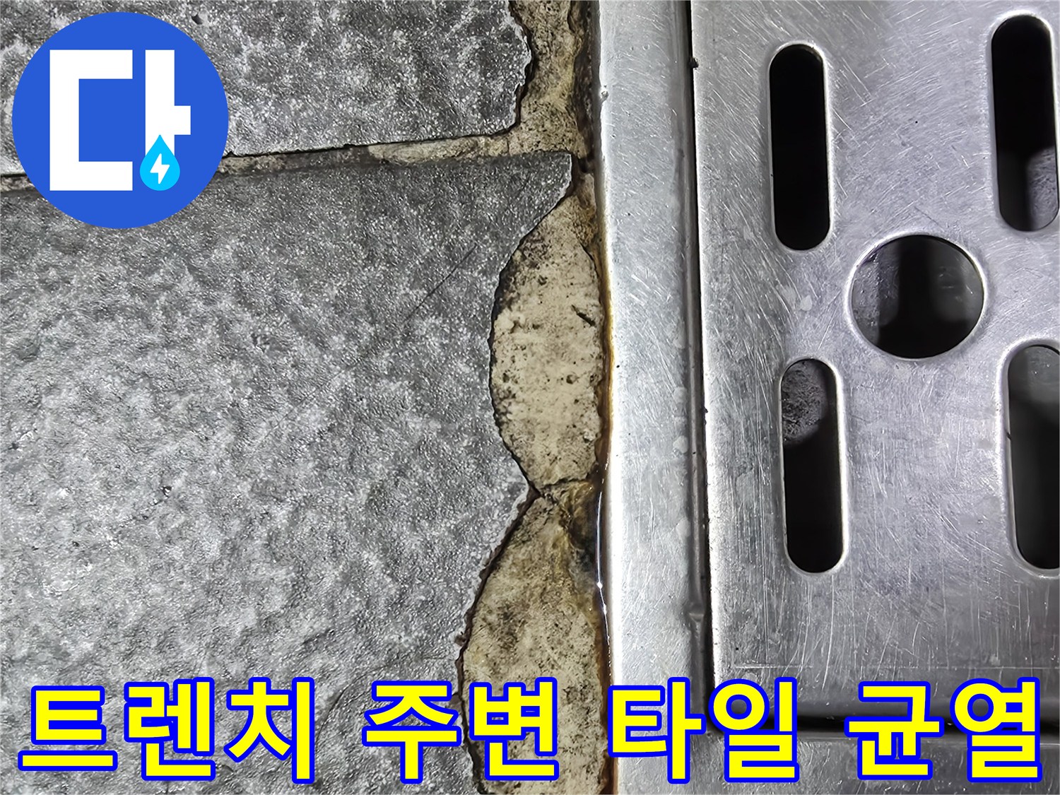금속 배수구 주변의 깨진 타일과 벌어진 틈새를 보여주는 사진입니다.