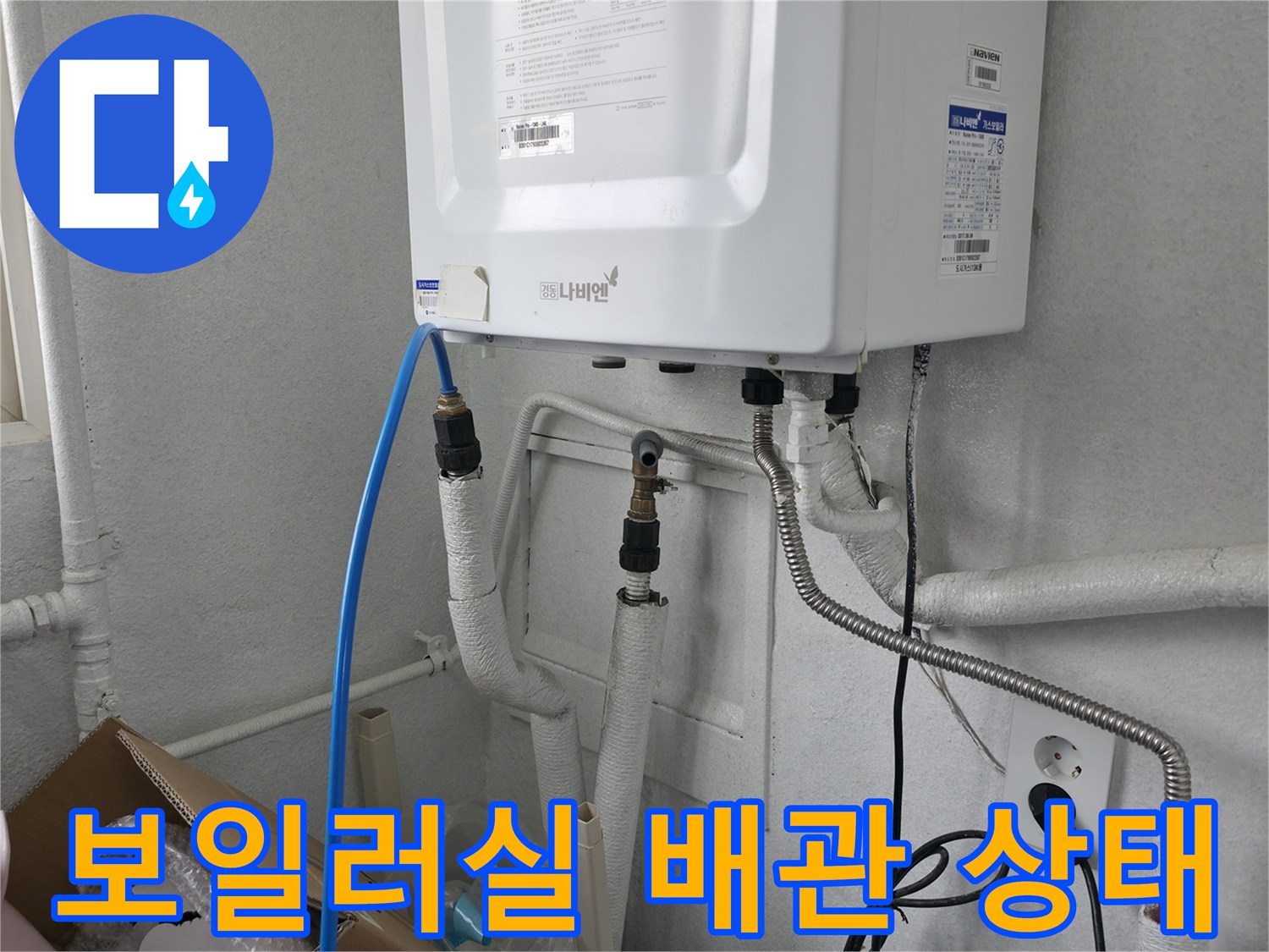 보일러 하단에 연결된 다양한 배관과 급수 호스의 모습