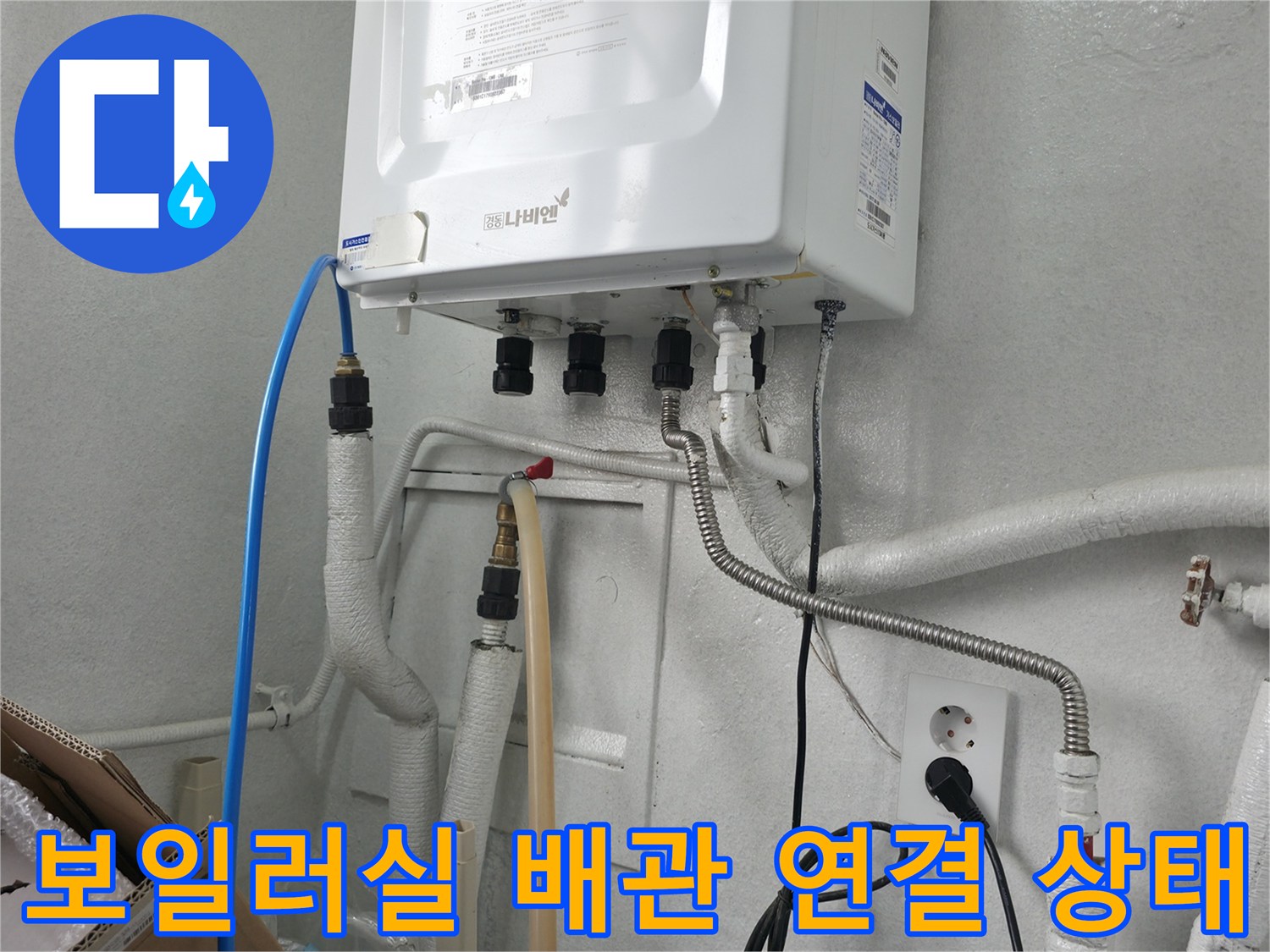 보일러 하단에 연결된 다양한 배관과 급수 호스의 모습입니다.